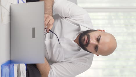 Vertical-video-of-Home-office-worker-man-focused-on-thinking.