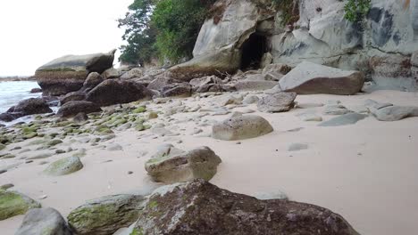 Sie-Bewegen-Sich-über-Einen-Felsigen-Strand-In-Richtung-Einer-Mysteriösen-Höhle-Mit-Weitläufigem-Wald-Und-Der-Andamanensee-Zur-Linken