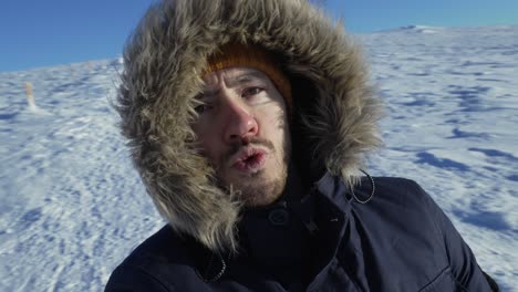 man recording his face in spinning selfie on a snowy mountain on a sunny day