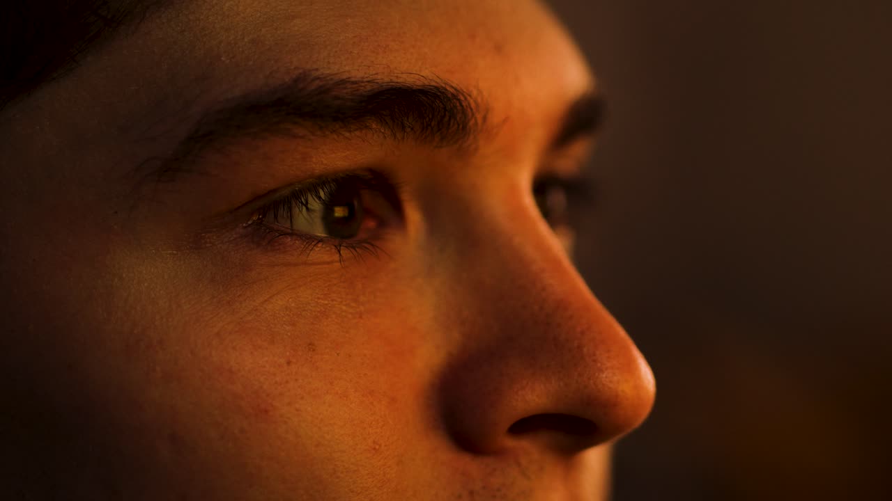 el hombre mira una pantalla mientras su cara y ojos están iluminados por ella