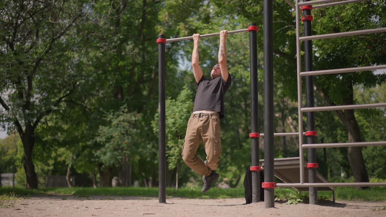 Individual Executes Vigorous Pullups Outside, Person Performs Strenuous Upper Body Exercises Outdoors, Determined Individual Trains Intensely On Outdoor Bars With Legs Tucked And Controlled Breathing