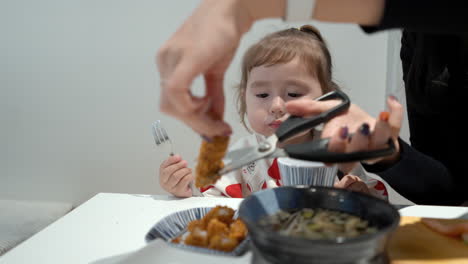 mother's hands cutting fried fish fillet into bite size pieces