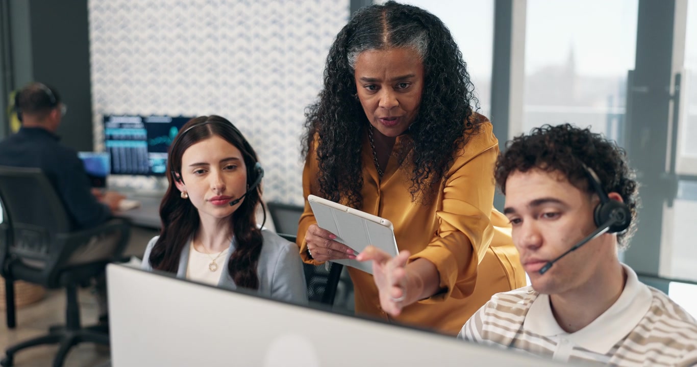 Manager Guiding Customer Service Representatives in Modern Office