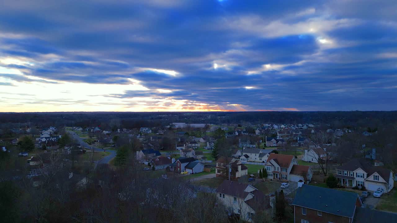 겨울 나무 위로 솟아 교외 지역과 아름다운 일몰을 보여줍니다.