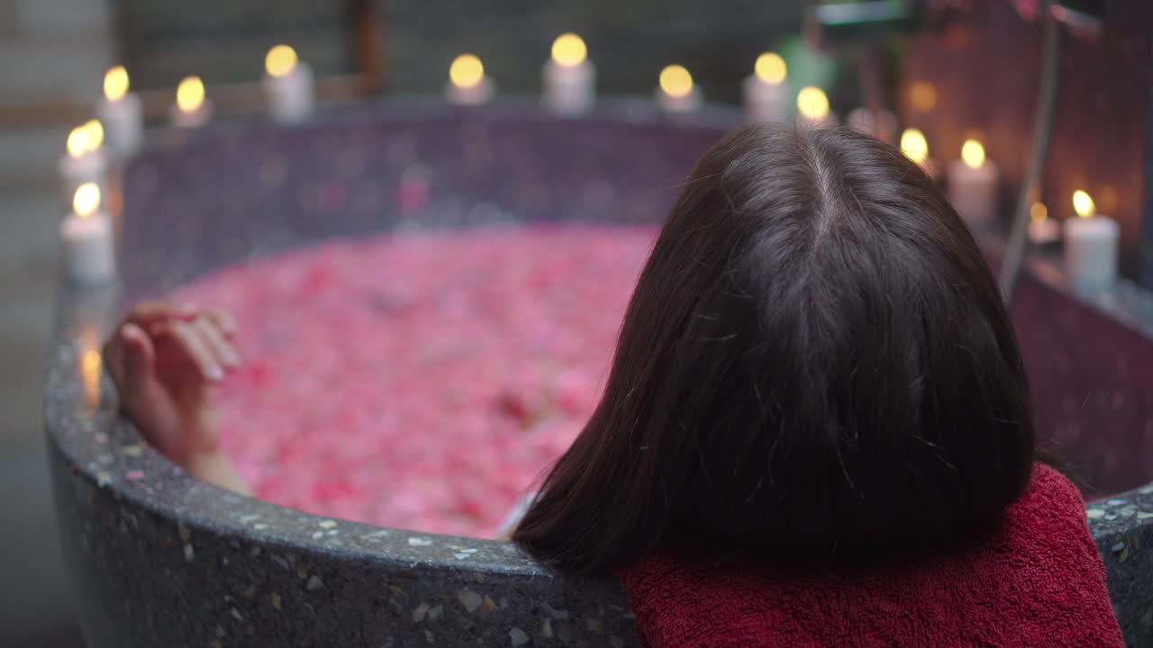 Woman enjoying a romantic bath with candles and rose petals