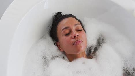 African-american-woman-relaxing-in-the-bath-tub-in-the-bathroom-at-home