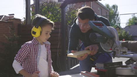 the father and his little son doing carpentry outdoor. slow motion