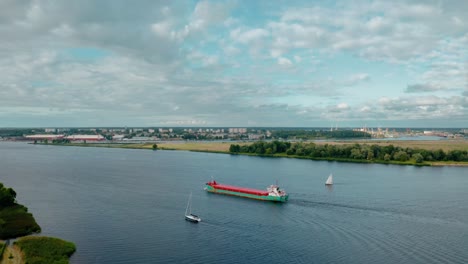 Aerial-view-of-cargo-ship-sailing-through-river-channel-into-open-waters