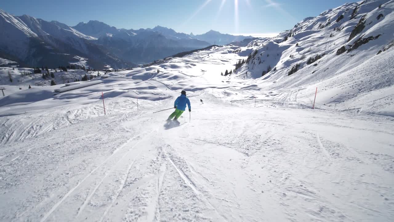 FOLLOW TRACKING SLOW MOTION: very good young skier skiing on a beautiful winter day on perfect slope with amazing mountain scenery at ski resort in the swiss Alps during cloudless day