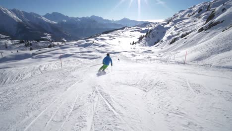 follow tracking slow motion: very good young skier skiing on a beautiful winter day on perfect slope with amazing mountain scenery at ski resort in the swiss alps during cloudless day