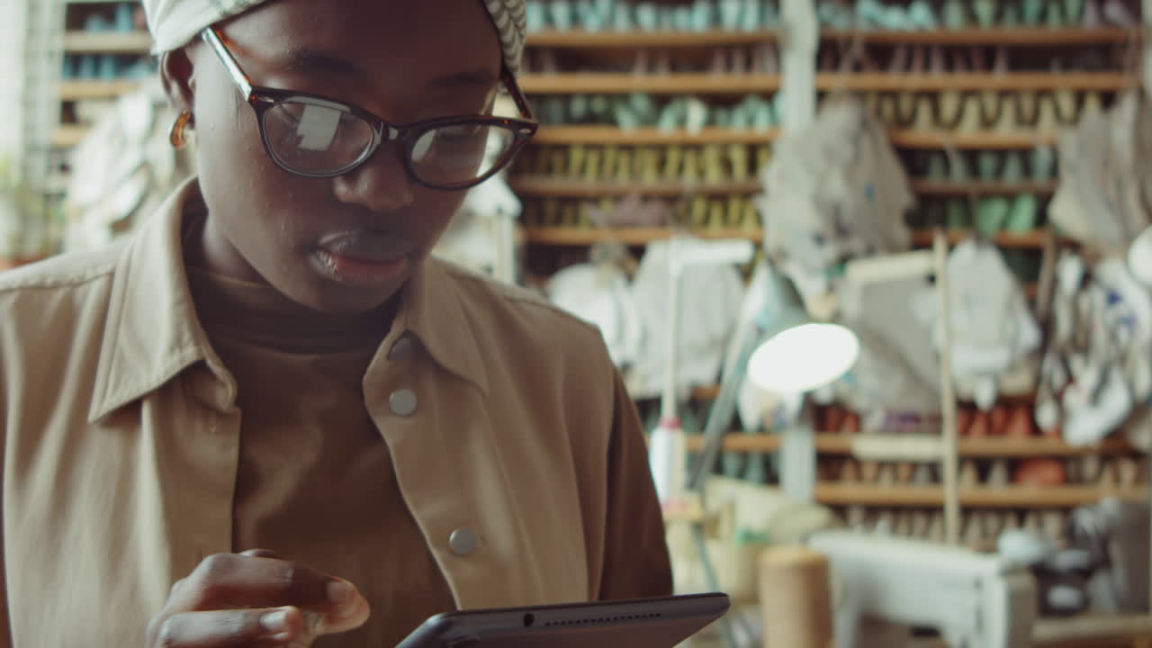 African American Woman Using Digital Tablet in Shoemaker Workshop