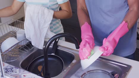 happy african american couple washing dishes in kitchen