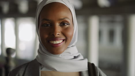 joyful black lady with hijab smiles to camera on city street