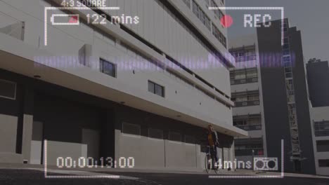 Animation-of-video-recording-interface,-with-woman-cycling-past-modern-building-in-the-sun
