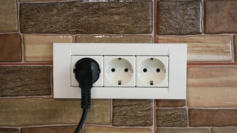 Woman's-hand-connecting-a-home-appliance-in-a-triple-power-wall-socket