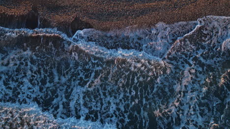 waves crashing onto the sandy beach during sunset on a calm evening