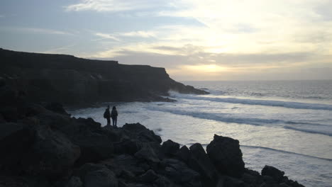 a couple is looking at the sunset in a beach in fuerteventura