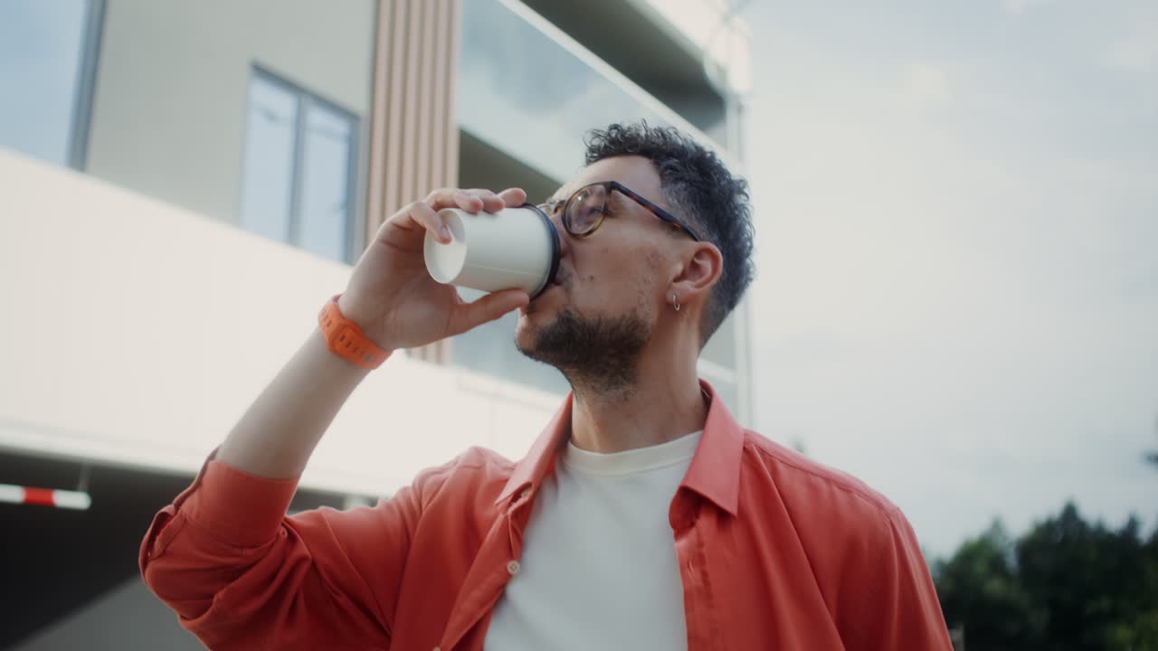 hombre bebiendo café frente a los apartamentos