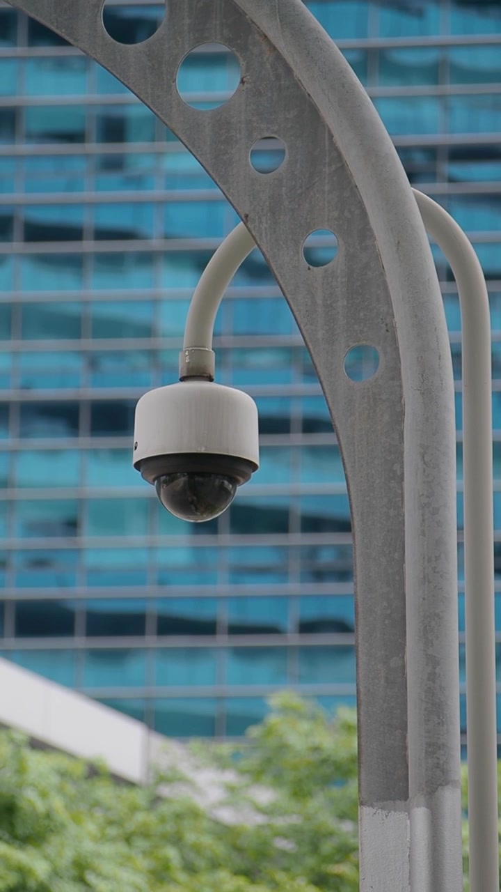 Security Camera Mounted on Metal Pole in Front of Modern Office Building