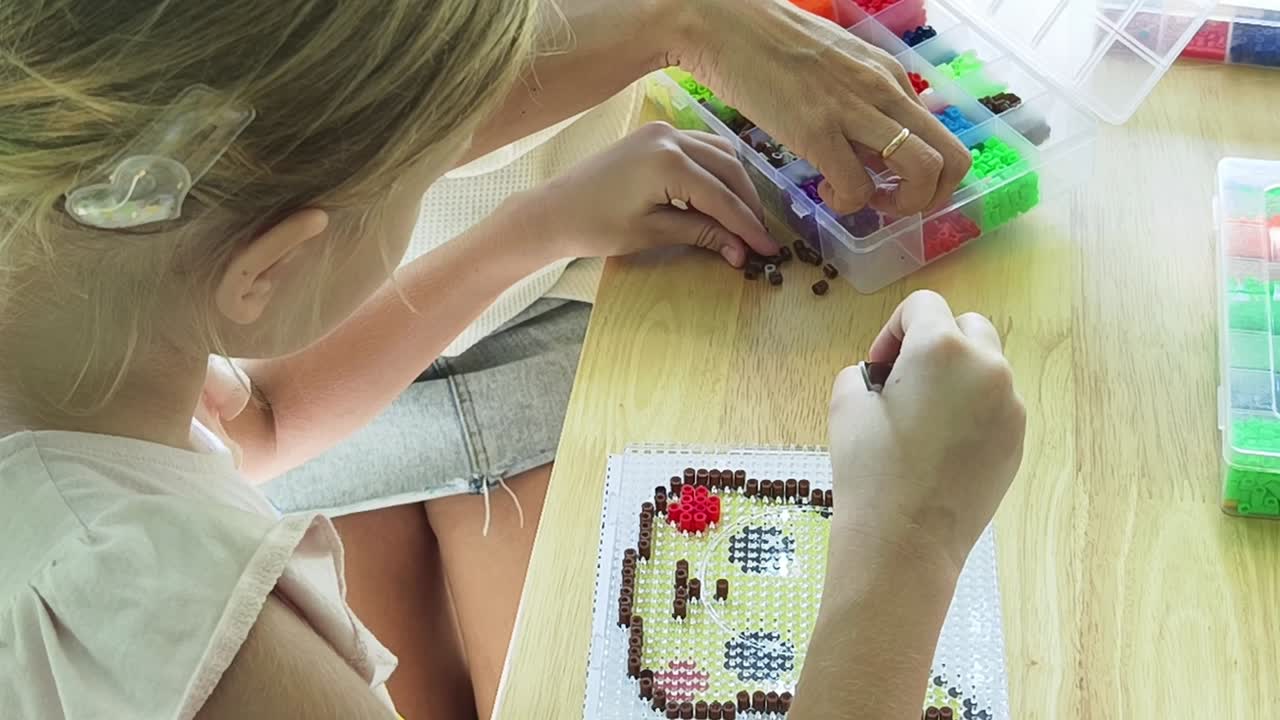 niño y adulto haciendo pixel art con cuentas