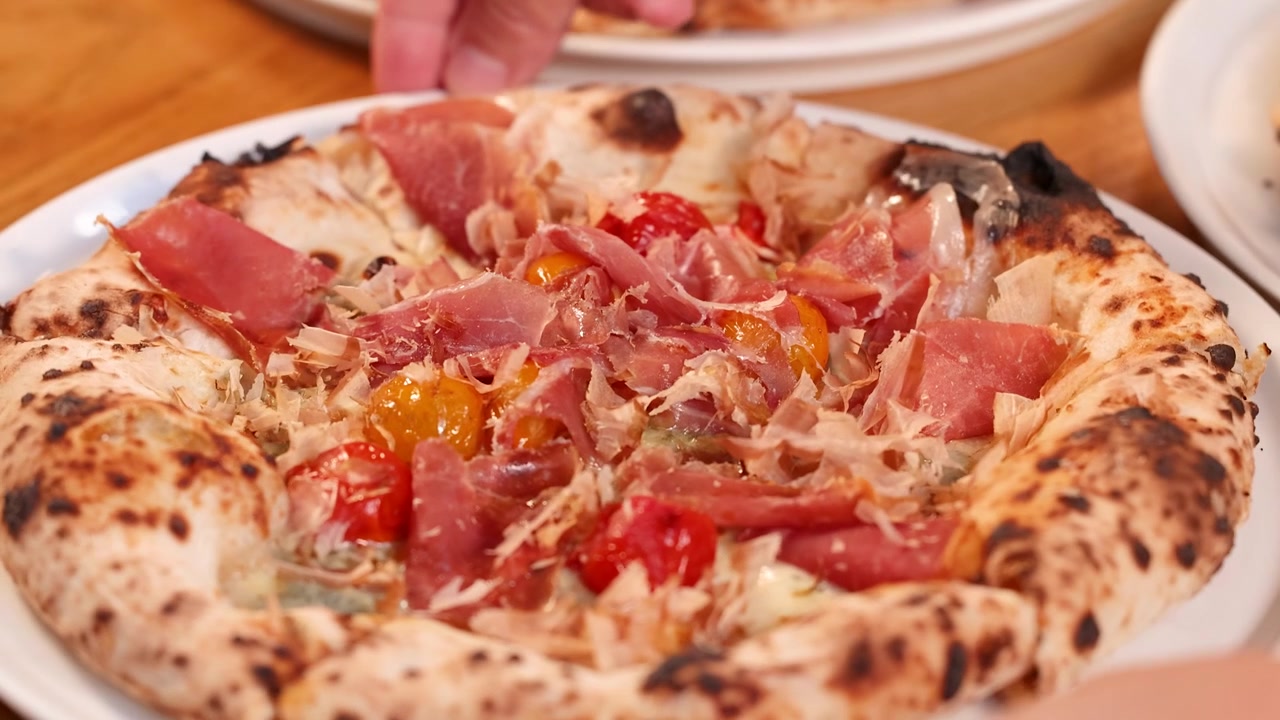 Primo piano di pizza gourmet su un tavolo con illuminazione interna calda e leggero movimento.