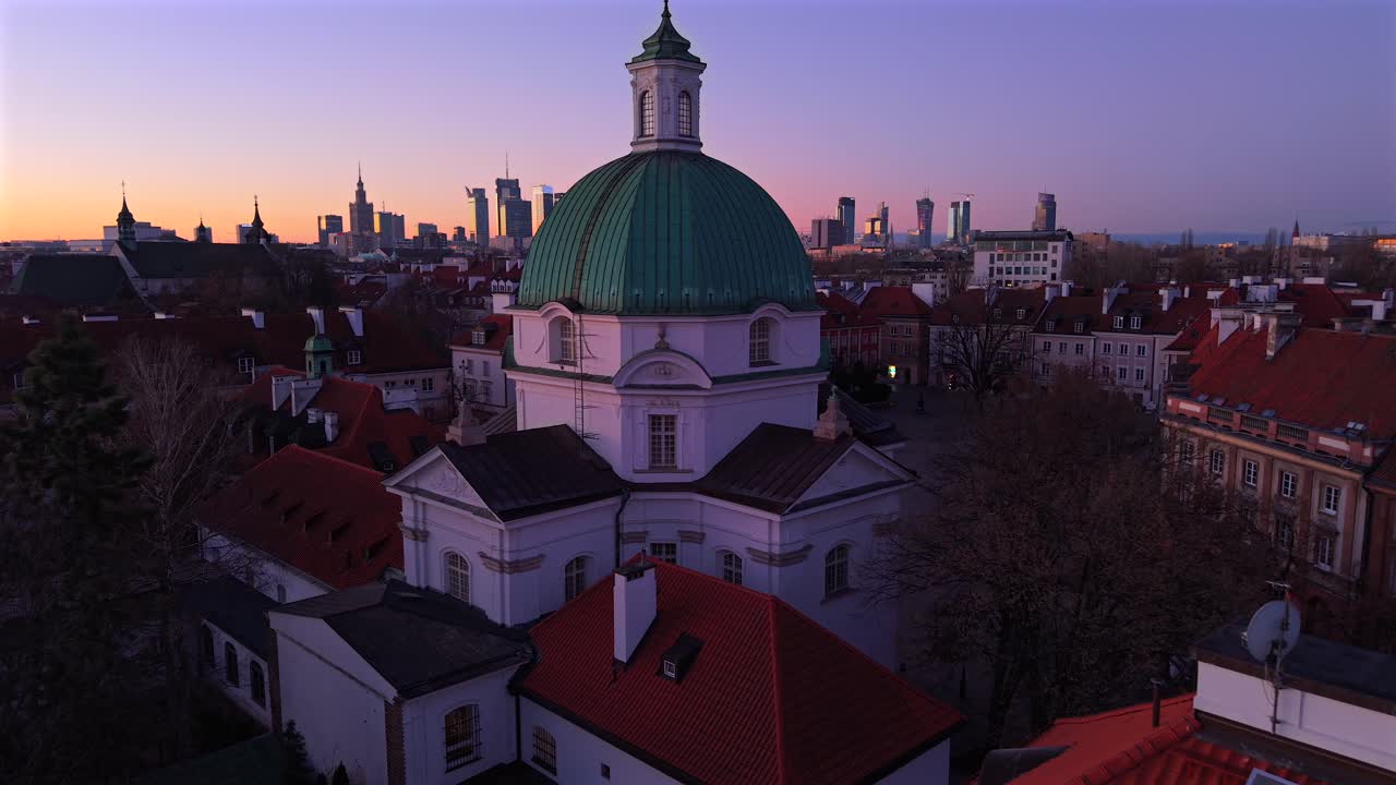 drone empujado a la izquierda sobre la iglesia de san casimiro con techos rojos y el horizonte de varsovia al amanecer