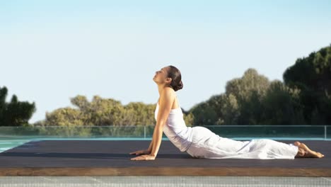 woman doing the upward facing dog pose by poolside