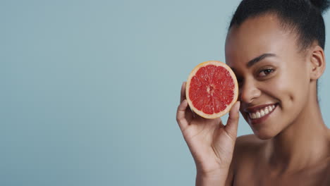 portrait attractive young african american woman holding grapefruit smiling enjoying natural healthy skincare essence beautiful female with perfect complexion on blue background
