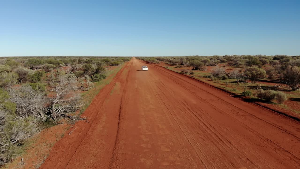 오스트레일리아의 외 사막에서 끝없는 직선의 자갈 도로를 여행하는 색 자동차.