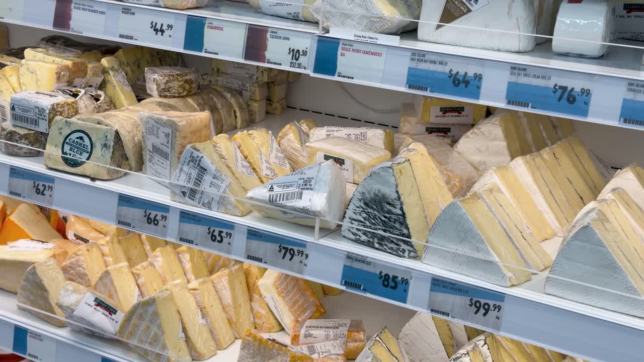 A smooth camera pan across refrigerated shelves stocked with various wedges of gourmet Australian cheese