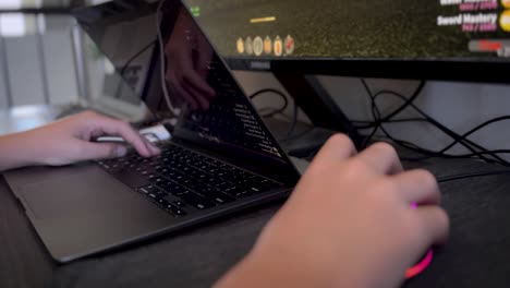 un niño usa un mouse y un teclado de computadora para juegos con dos pantallas