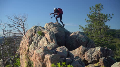 mujer joven con mochila y cámara fotográfica escalando en roca en un paisaje verde