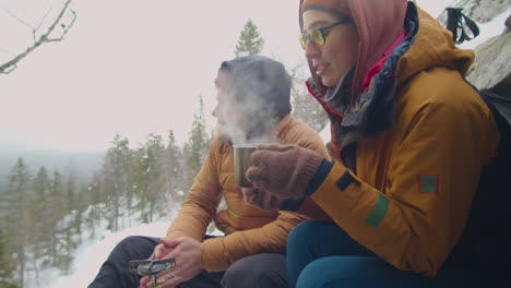 couple drinking hot tea at campsite in mountains