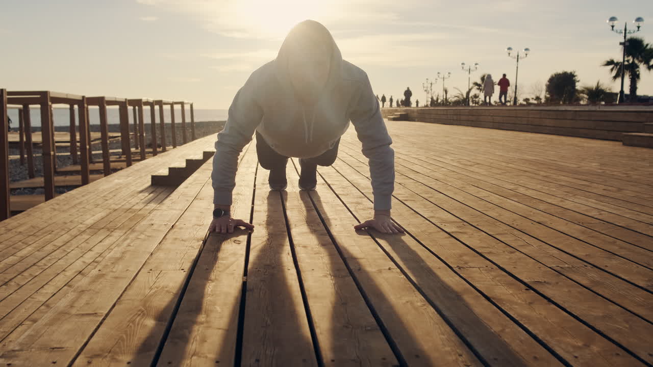 해변의 나무 갑판에서 푸시업을 하는 남자