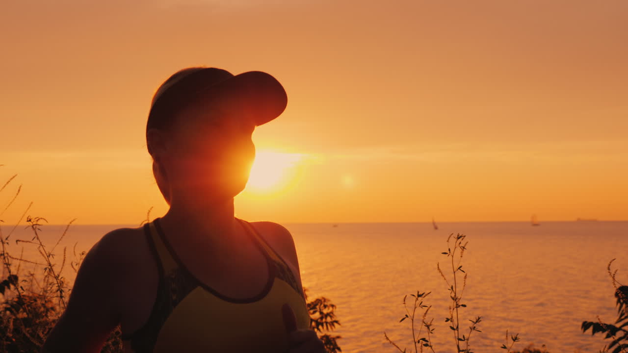 здоровая молодая женщина совершает пробежку на фоне моря и заходящего солнца