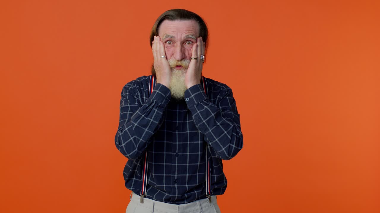 emocionado asombrado anciano levantando las manos en sorpresa mirando a la cámara, conmocionado por la victoria repentina