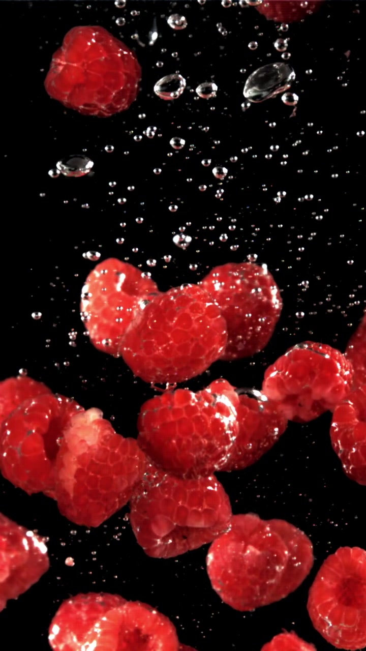 Fresh Red Raspberries Floating in Water with Bubbles on Black Background