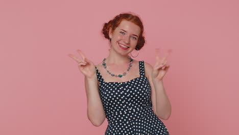 redhead young woman showing victory sign, hoping for success and win, doing peace gesture, smiling