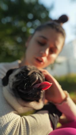 woman hugging a pug in a park