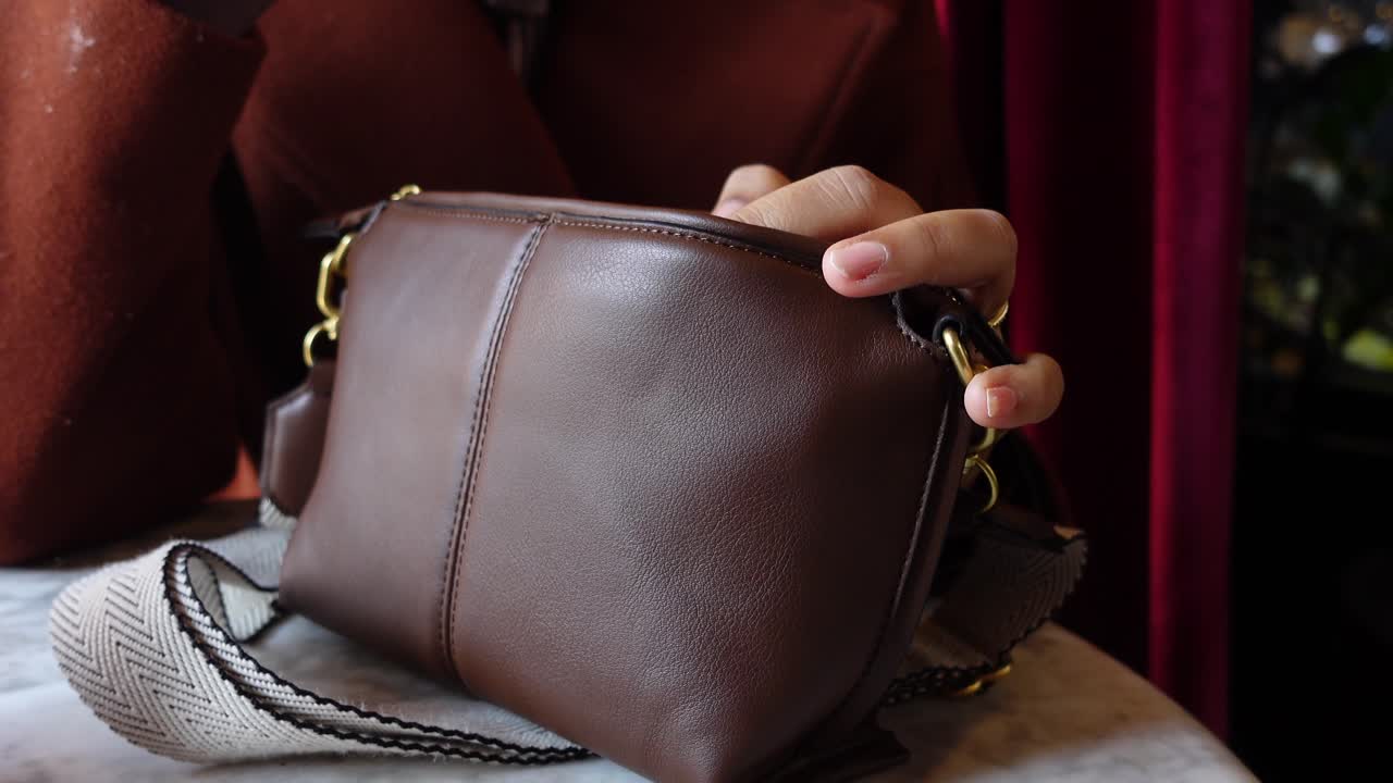 갈색 가죽 어깨 가방 을 들고 있는 여자