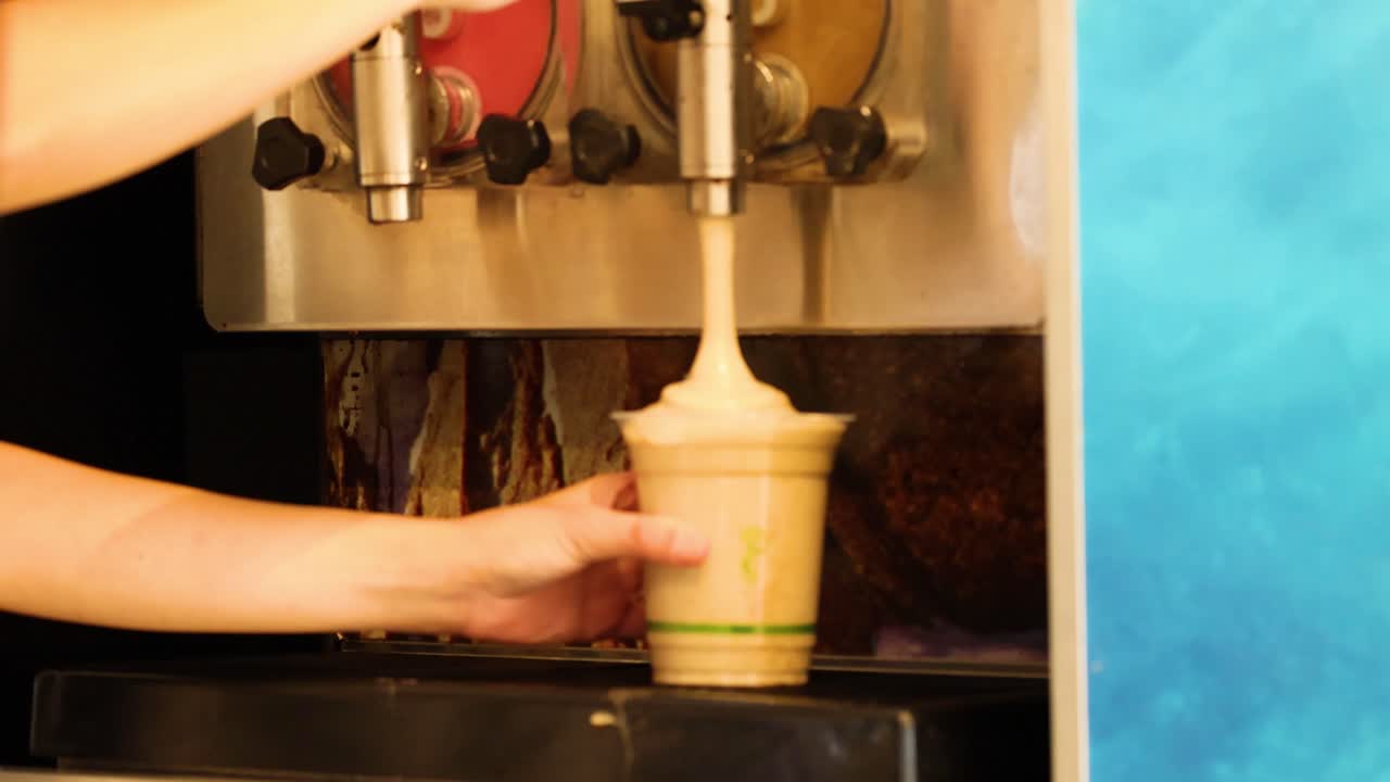 Tangan mengisi gelas dengan minuman es serut