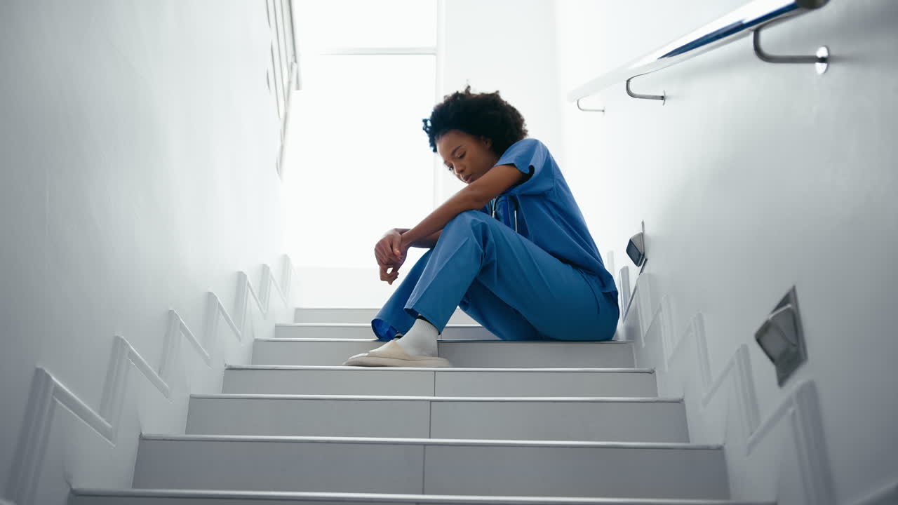 Infirmière stressée et fatiguée en tenue médicale assise dans les escaliers à l'hôpital