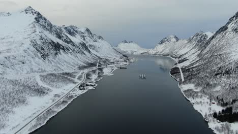 Drohnenansicht-In-Der-Gegend-Von-Tromso-Im-Winter,-Die-über-Einen-Fjord-Fliegt,-Der-Von-Weißen-Bergen-In-Norwegen-Umgeben-Ist