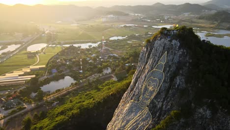 imágenes aéreas de 4k de arriba hacia abajo de la imagen de buda tallada hecha de oro en un acantilado en khao chee chan, pattaya, tailandia