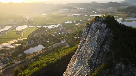 4k top down aerial footage of carved buddha image made from gold on a cliff at khao chee chan, pattaya, thailand