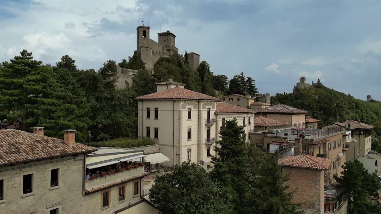 Aerial drone, cinematic views of San Marino's city center, showcasing the majestic Fortress of Guaita, historic architecture, stunning hilltop landscapes surrounded by breathtaking panoramic vistas