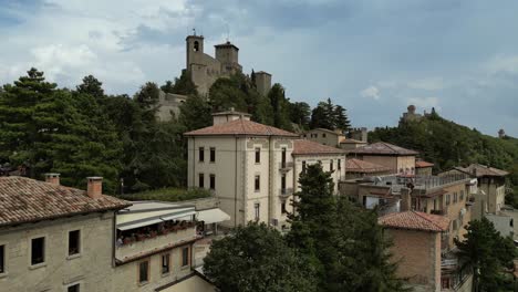 aerial drone, cinematic views of san marino's city center, showcasing the majestic fortress of guaita, historic architecture, stunning hilltop landscapes surrounded by breathtaking panoramic vistas