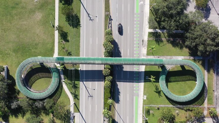 An aerial view directly over a pedestrian walkway which crosses a six lane highway on a sunny day in Florida