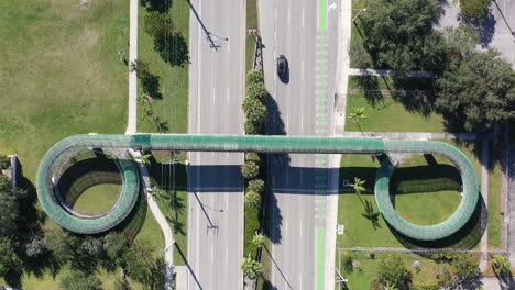 Una-Vista-Aérea-Directamente-Sobre-Una-Pasarela-Peatonal-Que-Cruza-Una-Autopista-De-Seis-Carriles-En-Un-Día-Soleado-En-Florida