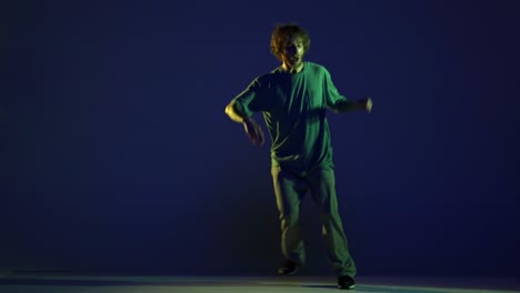 stylish young man, hip-hop dancer dancing isolated over dark blue background in neon light. modern dance art, fashion, youth, ad, style. 4k, video